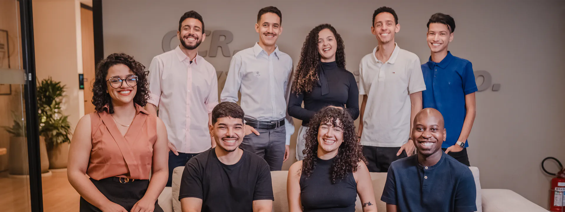 Grupo de estagiários, composto por três mulheres e seis homens, todos sorrindo e demonstrando alegria