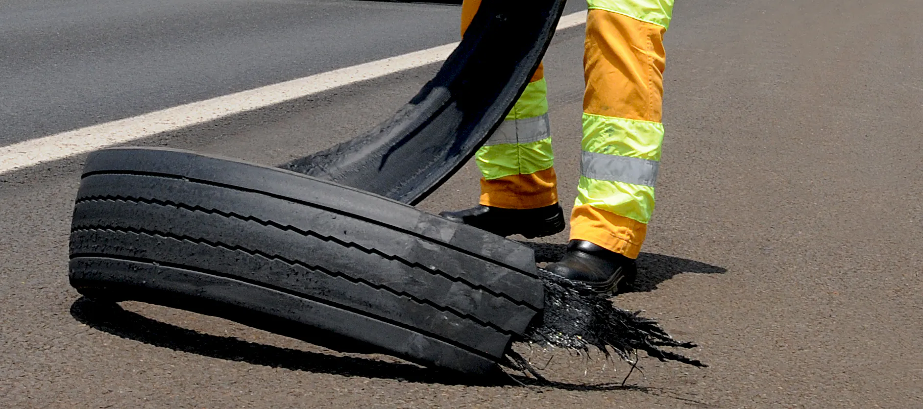 Imagem de um pneu de boracha estraçalhado em uma rodovia
