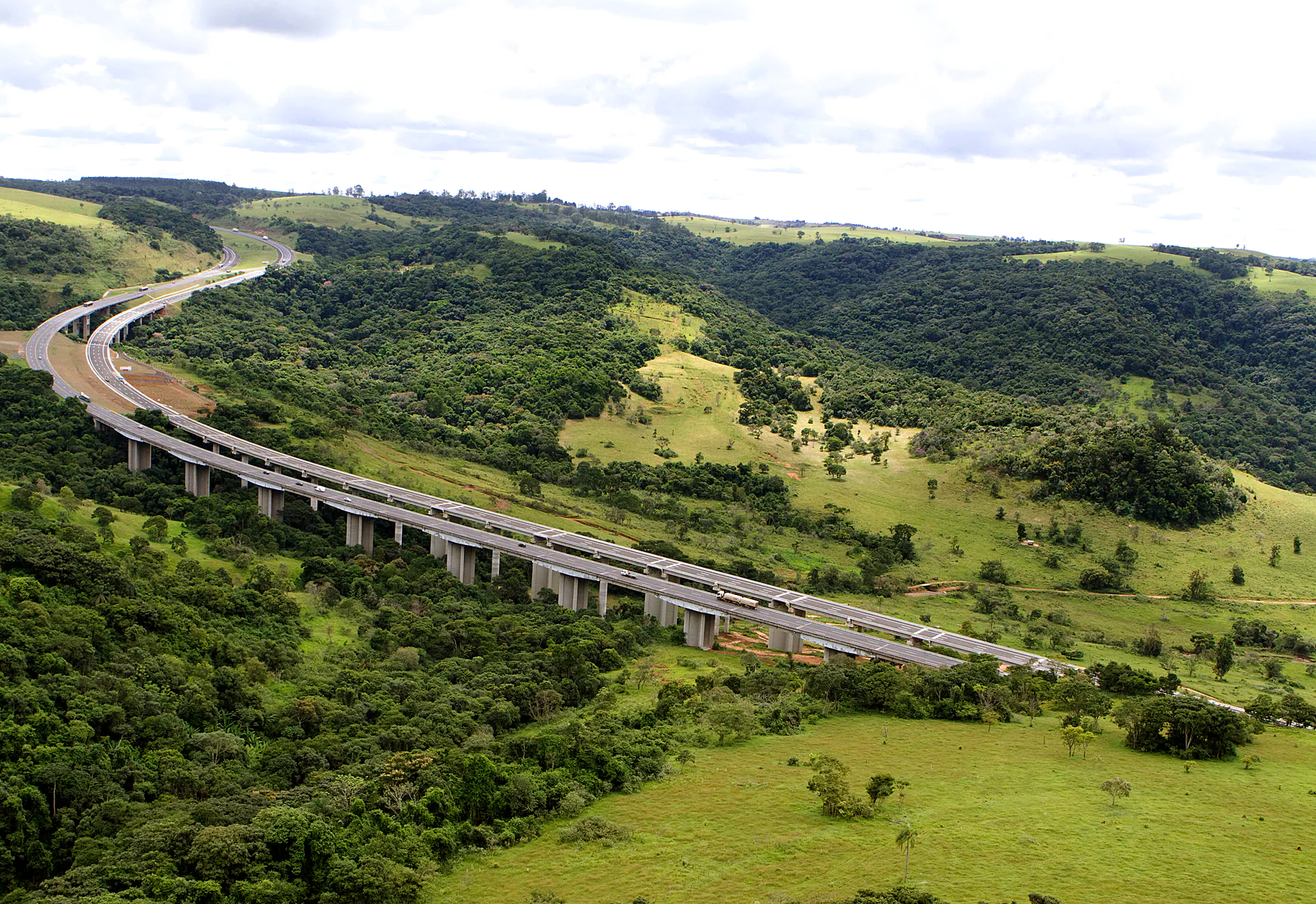 Vista aérea de veículos andando por uma rodovia ladeada por vegetação