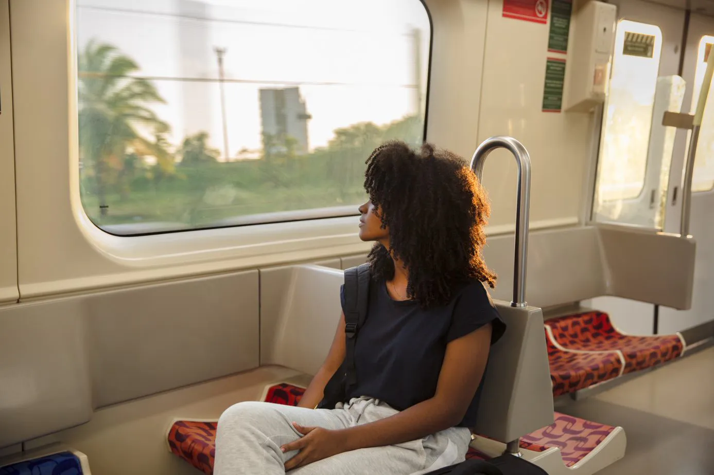 Mulher sentada em um vagão de metrô olhando para fora pela janela