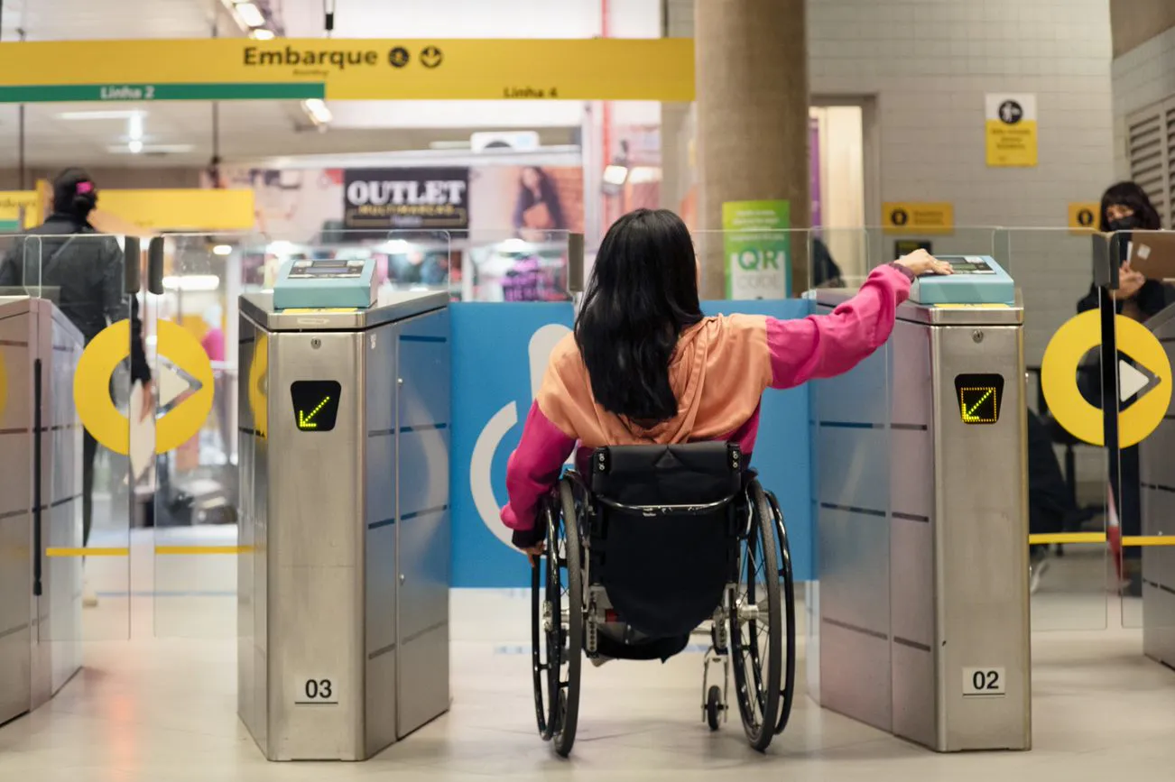 Mulher cadeirante passando por uma das catracas da estação de metrô