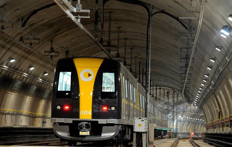  Imagem de  um metrô em funcionamento em cores preto e amarelo em um túnel.
